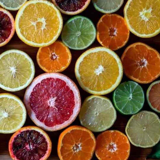 variety of citrus fruits halved on cutting board beside juicer